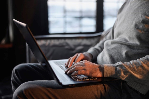 person working on a laptop while sitting on a non-ergonomic couch