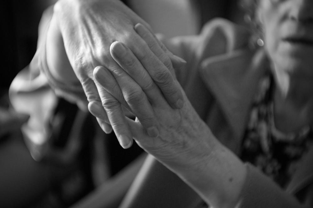A woman helps a Parkinson’s patient stretch out their hand.