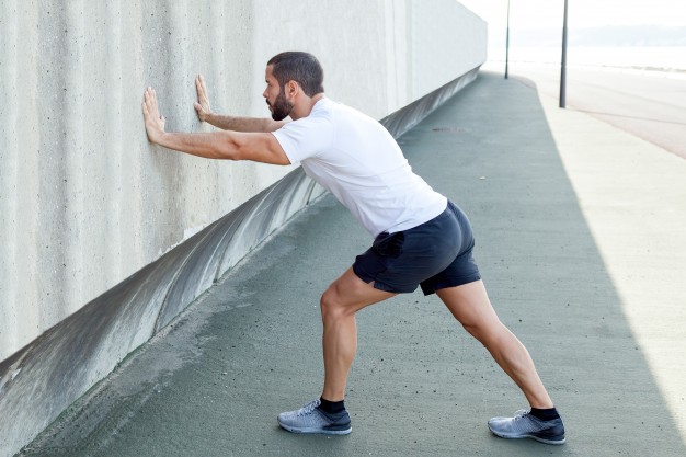 patient with knee pain doing heel and calf stretches