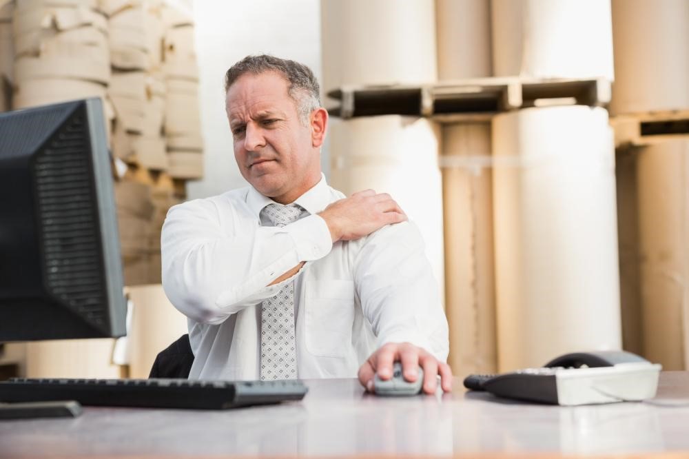 man experiencing shoulder pain at work