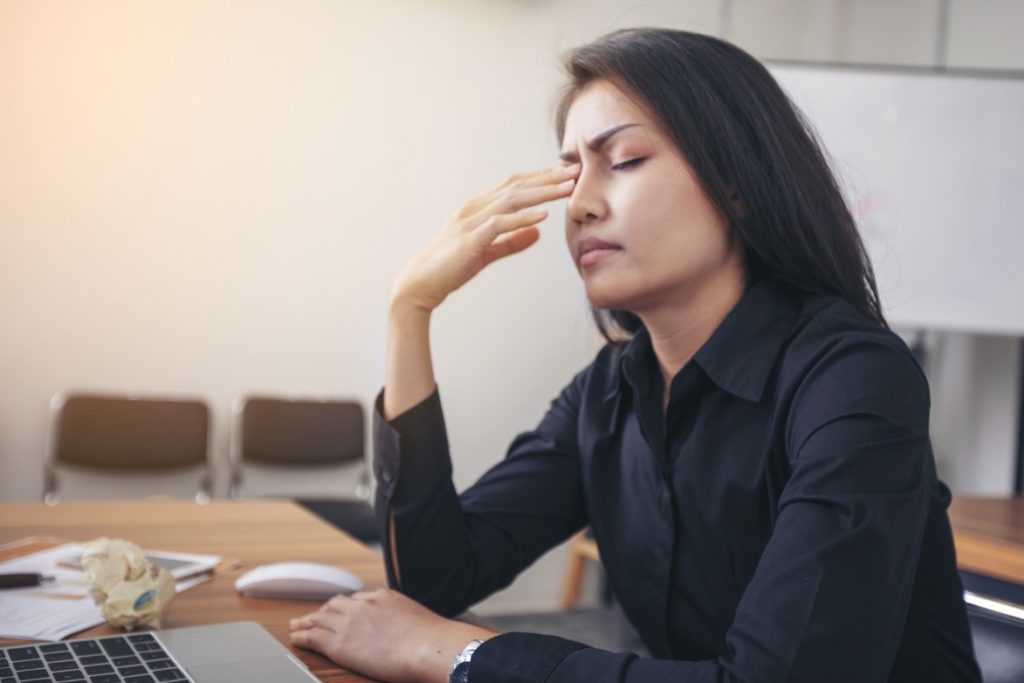 A woman experiencing a vestibular migraine at her work desk.