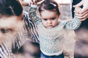 Woman holding infant girl’s hands