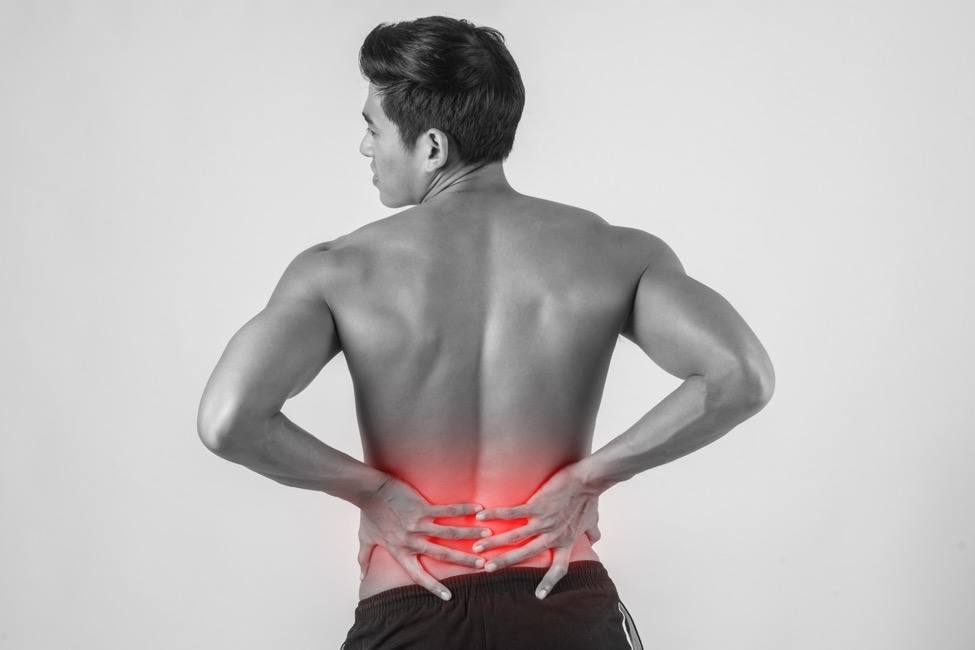 A person with back pain holds their waist in pain.