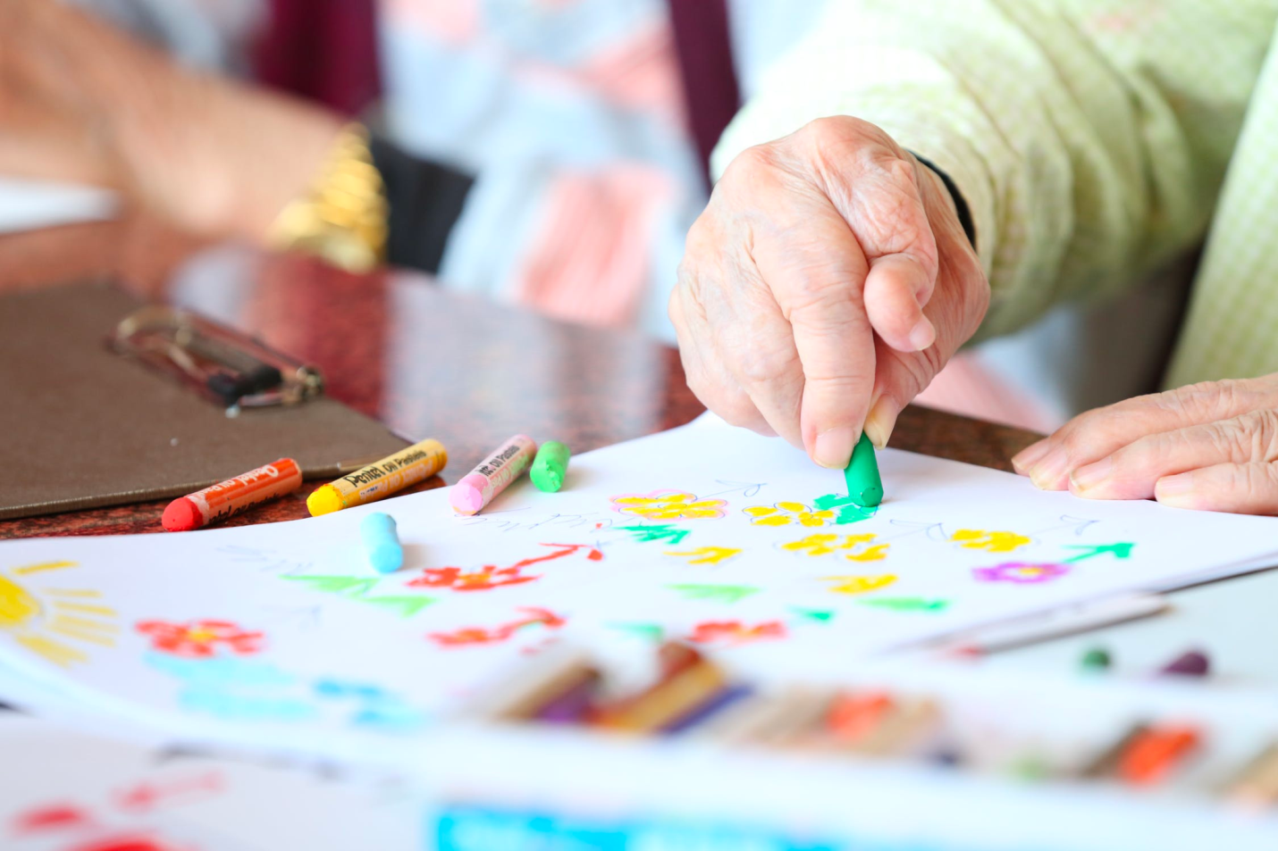 A person with an arthritic hand holds a crayon while coloring.