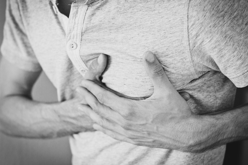A man places his hands on his chest due to pain.