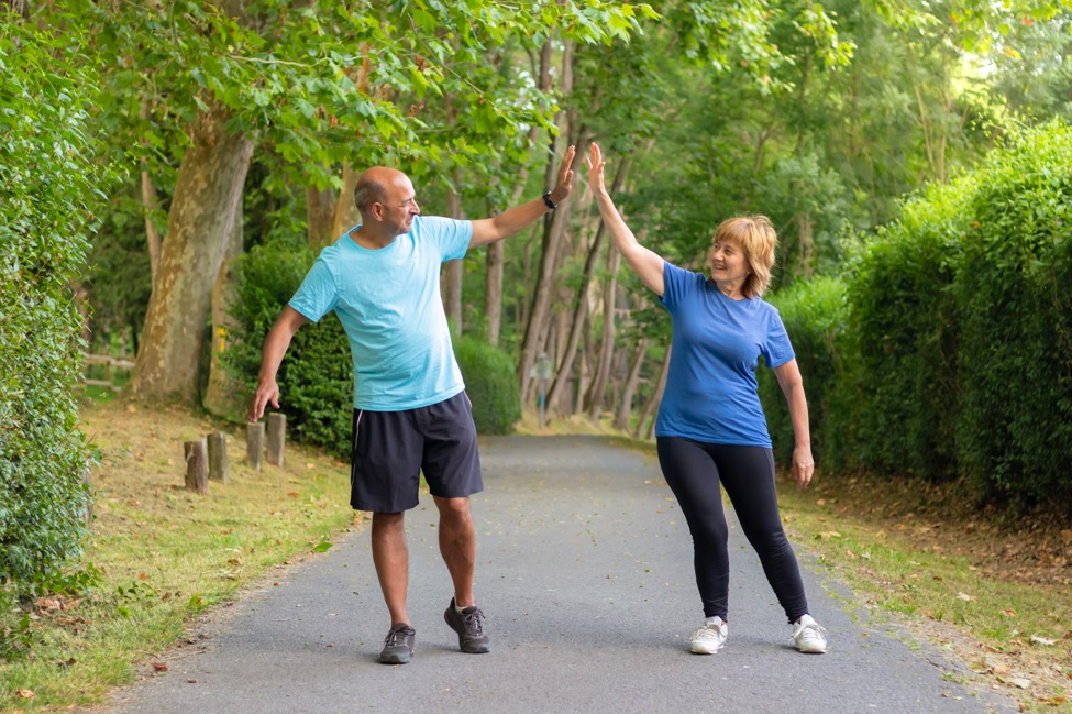 An older couple walking along a path and giving each other a high-five