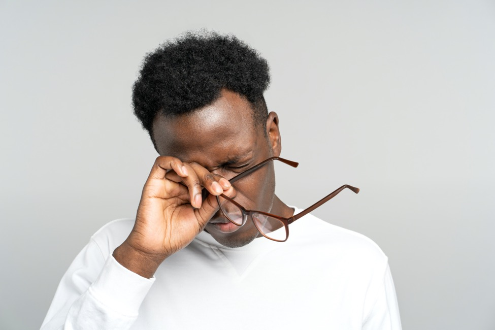  a man rubbing his eyes with his glasses off