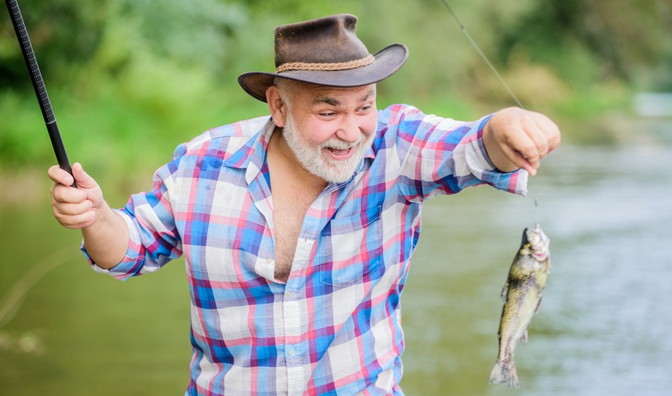 man in plaid shirt and fedora lifting a fish using his shoulder