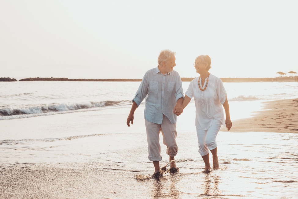 man and woman walk on beach recovering from back pain