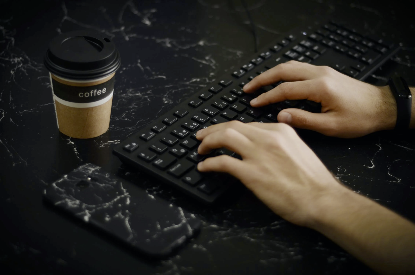 A person’s hands type on their keyboard, indicating a lack of carpal tunnel.