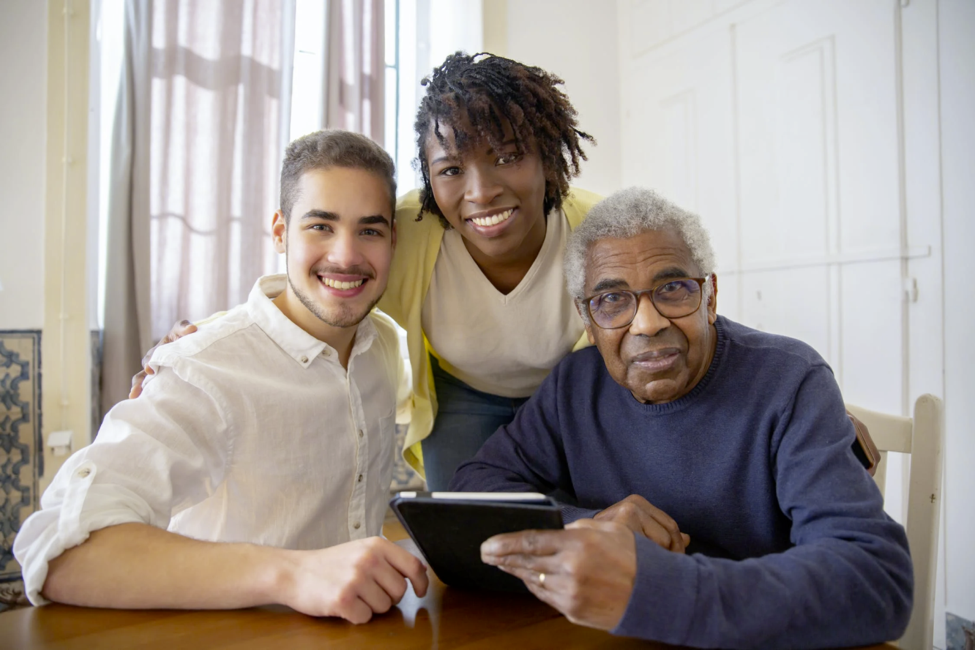 An older patient smiles while sitting with his family.