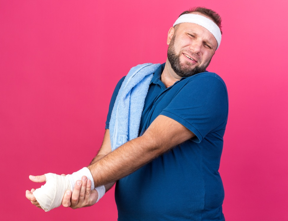 a man in a blue shirt holds his broken hand