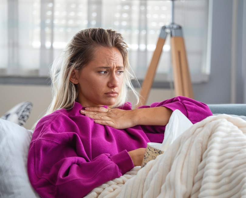 woman on couch holding neck looking concerned