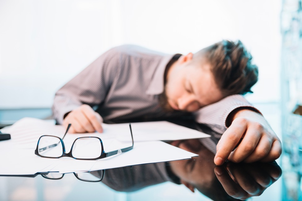 a man sleeping at his desk with his glasses on some papers