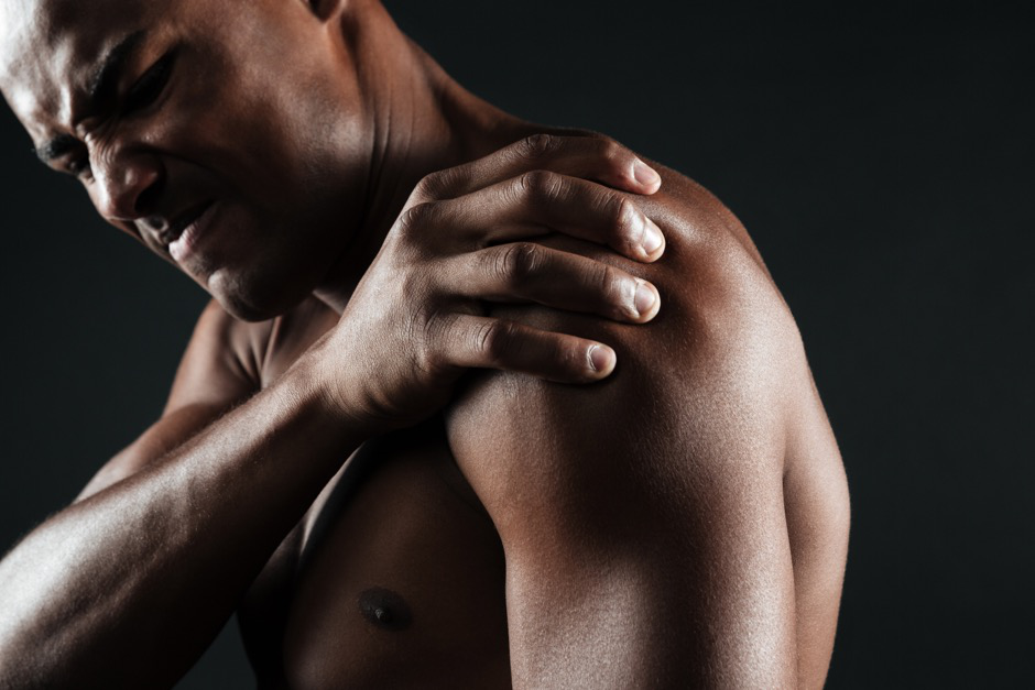 Man holds his shoulder because of pain.