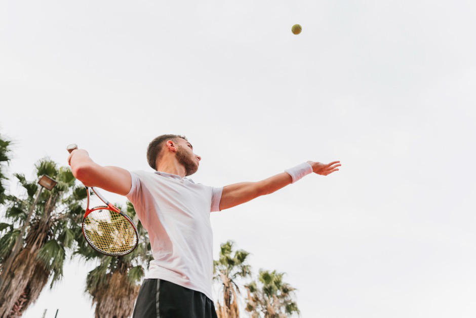 Man serving a tennis ball after shoulder surgery.