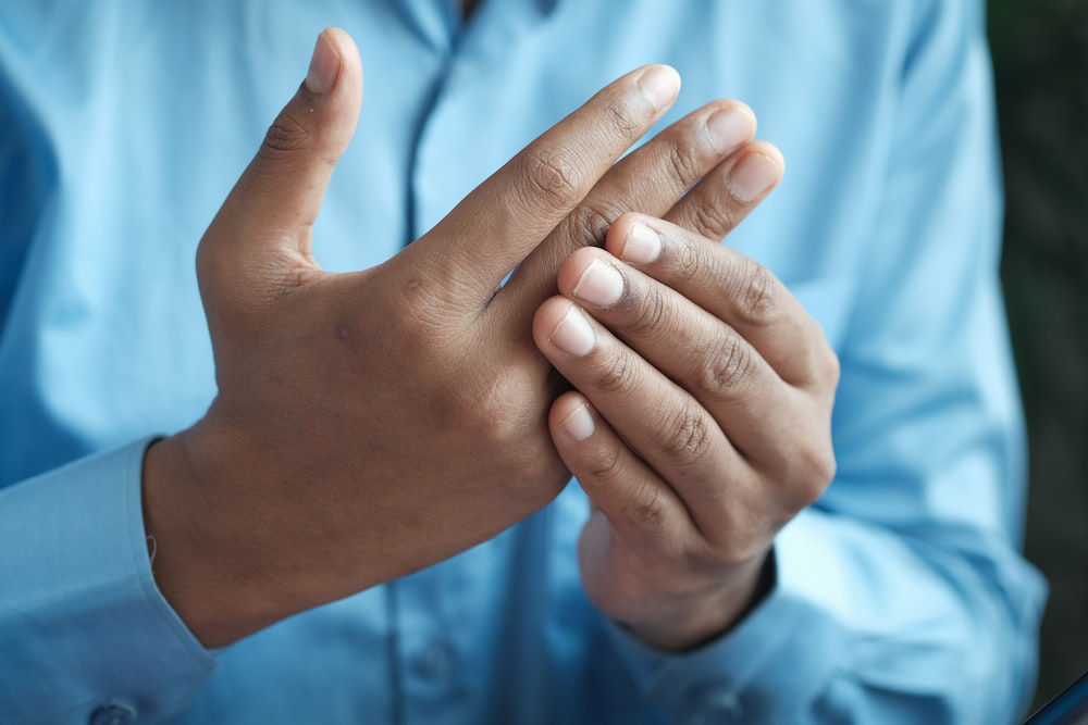 Man in blue shirt holds his hand affected by pseudogout arthritis.