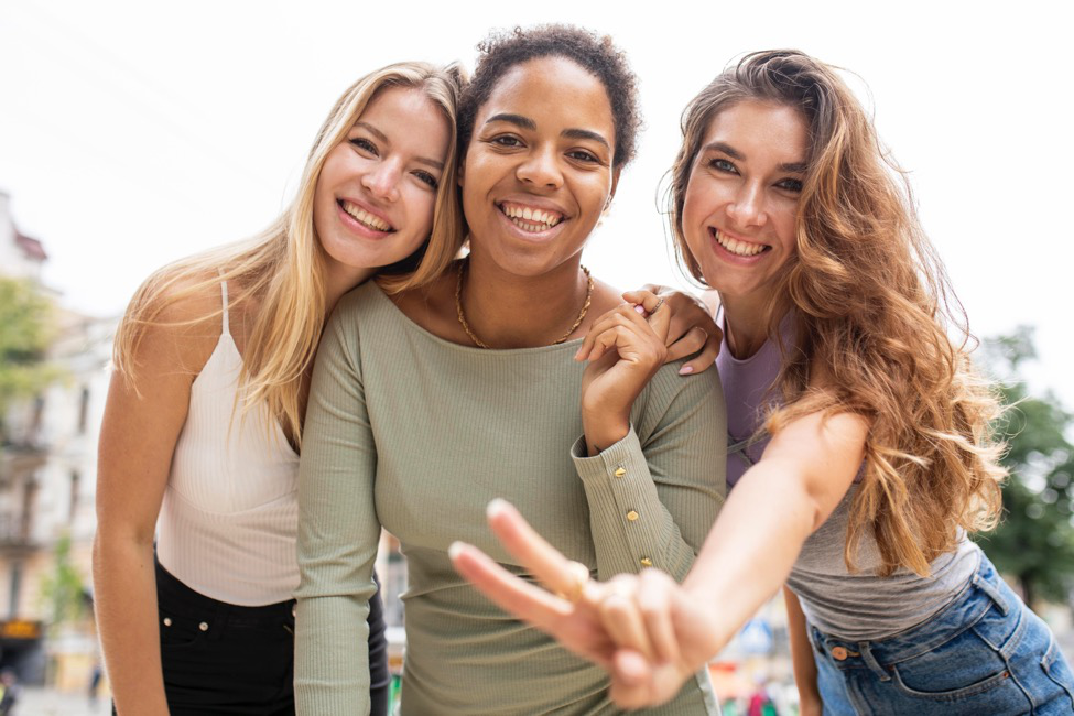 Three women smiling, hugging, and laughing.