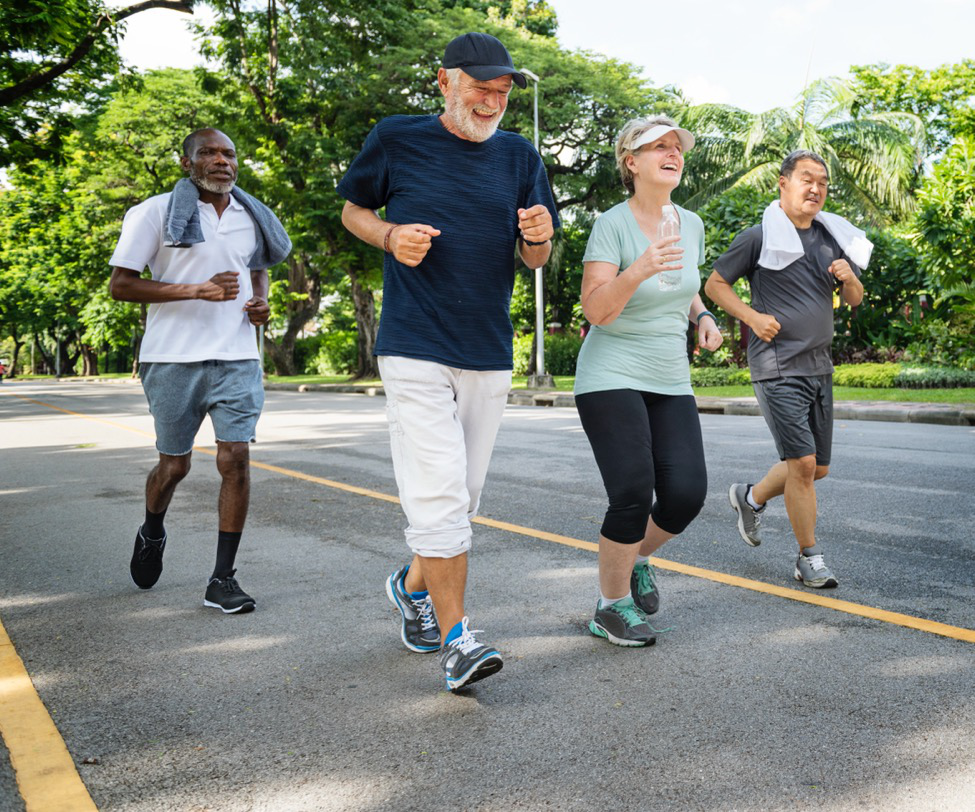 Four senior citizens jogging along a track.