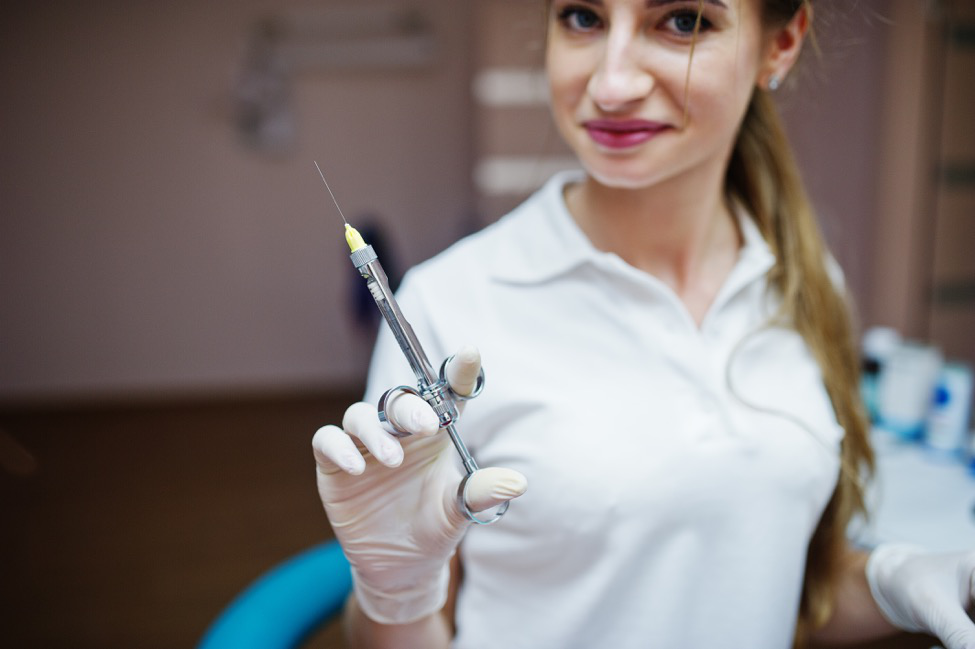 A female nurse holds a needle with a local anesthesia.