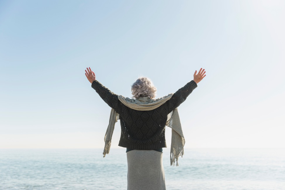 woman stands on beach with a healthy back after surgery for interlaminar implants