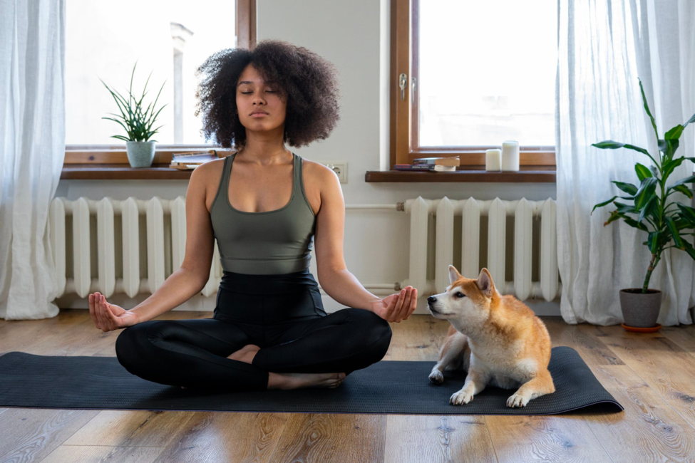 A healthy young woman meditates while sitting on her yoga mat.