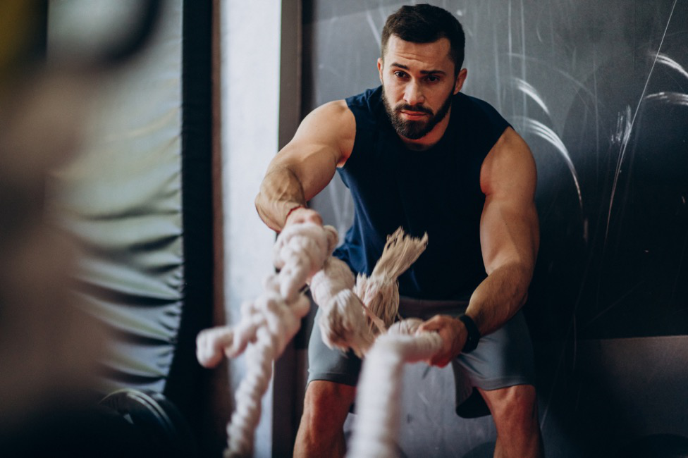 A man exercises with a battle rope.