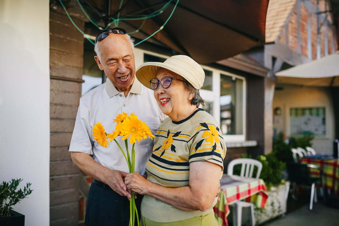 An old couple holding yellow flowers