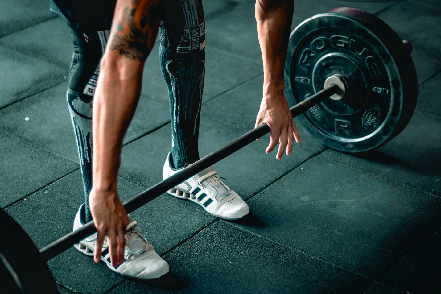 A person safely lifts a barbell to perform a deadlift.