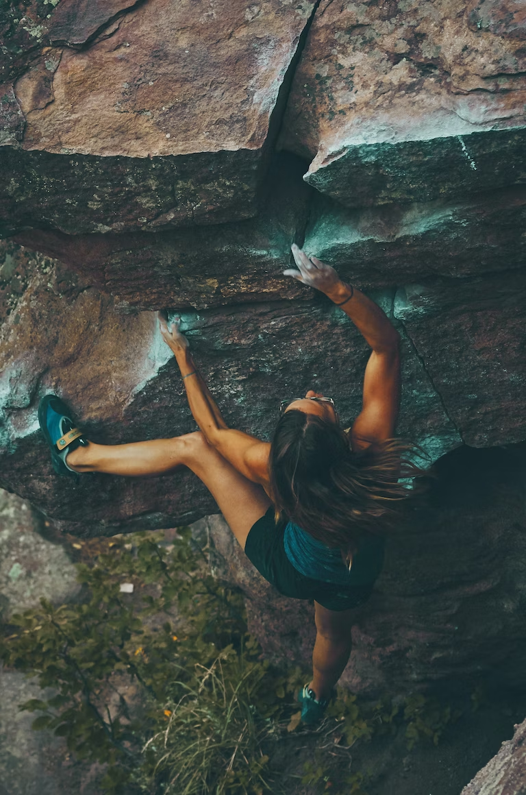 A woman climbs a rock to stay fit and active.