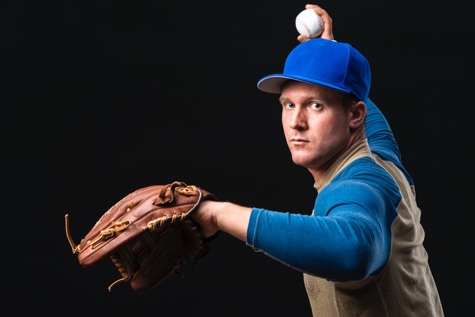 Man in a baseball uniform gets ready to throw a baseball