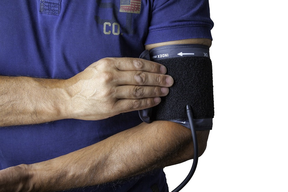 A man with a blue shirt wears a blood pressure monitor