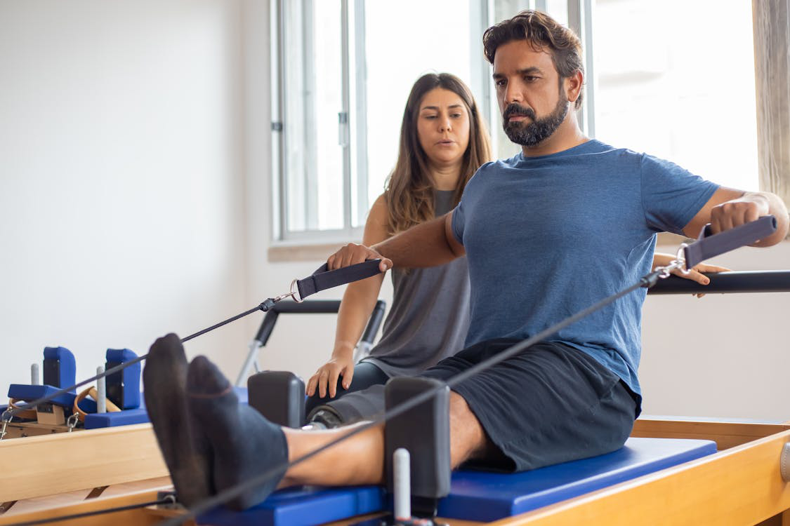 A man exercising with the help of a physical therapist.