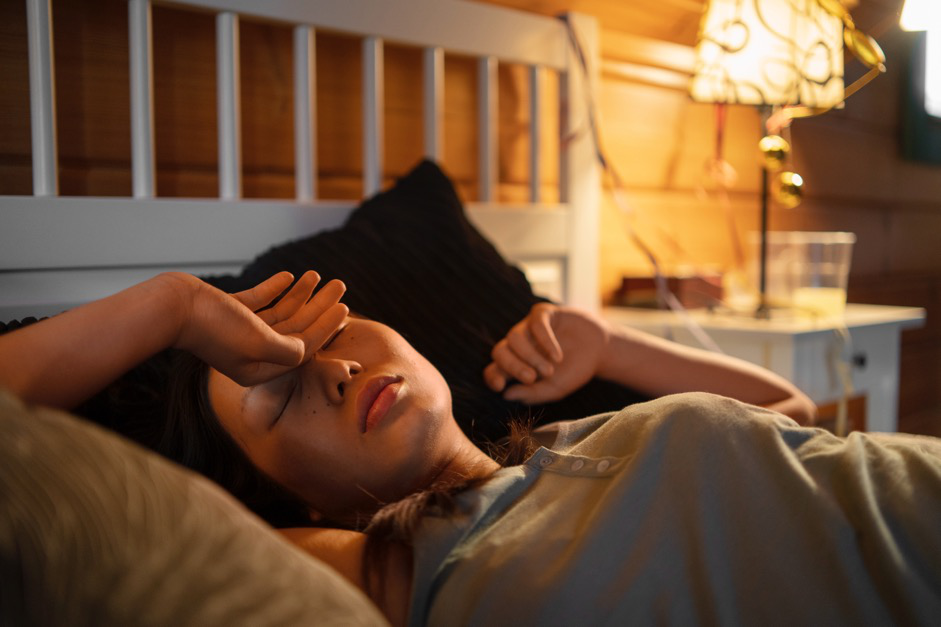 A young woman with fatigue lies in bed