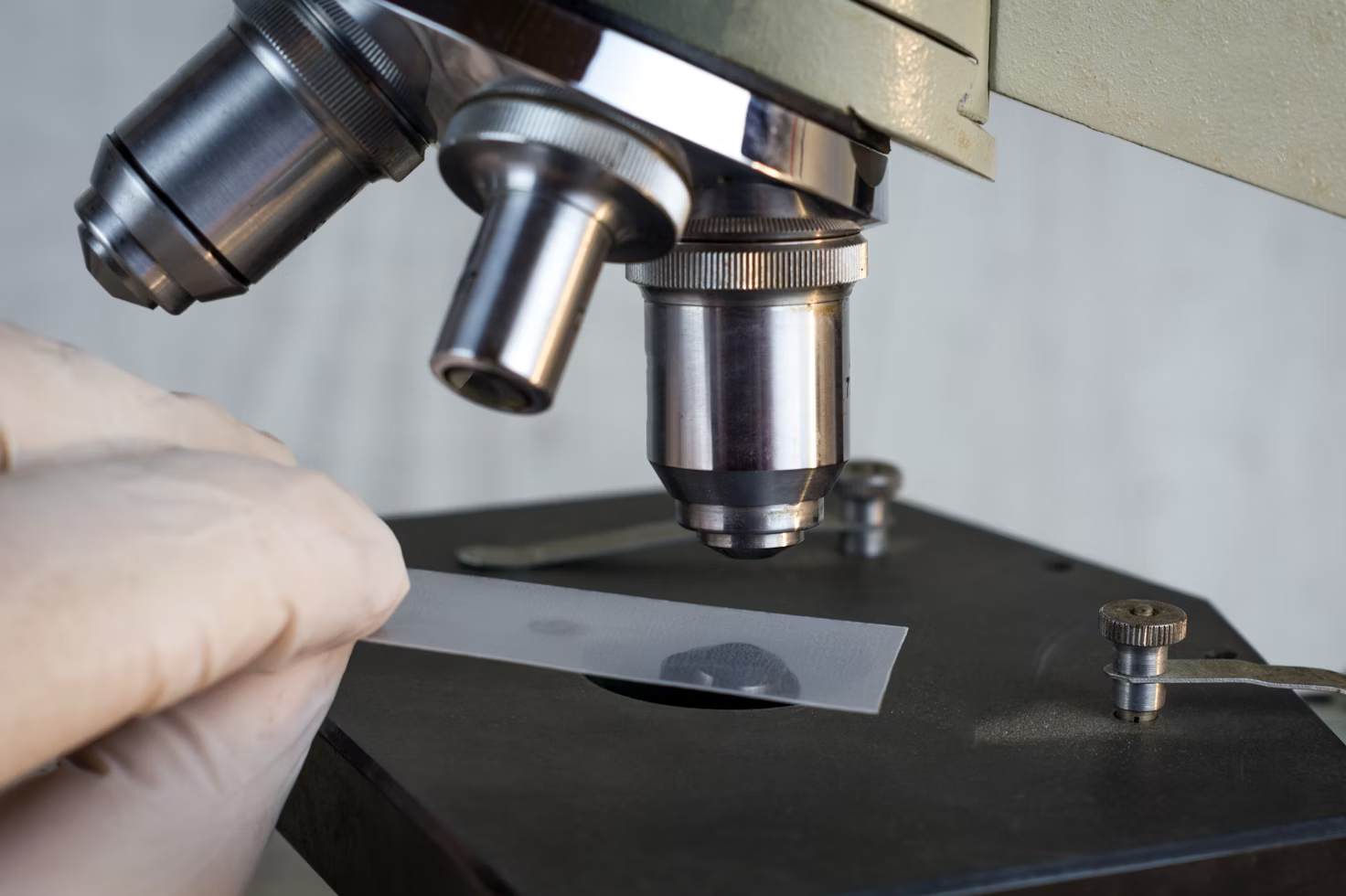 A lab worker places a slide underneath a microscope