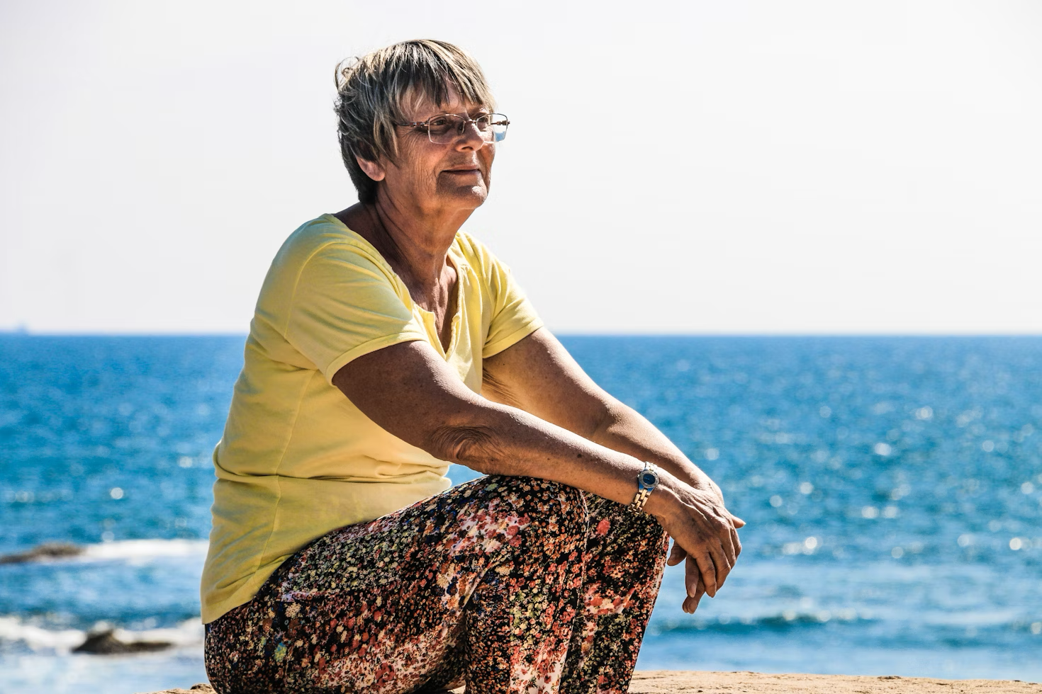 an elderly woman sitting on a beach