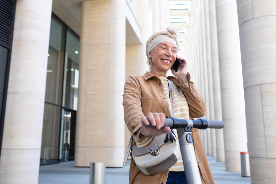 a woman talks on the phone while riding an electric scooter