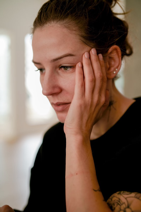 A woman holding her head and showing signs of distress, indicating psychogenic pain.
