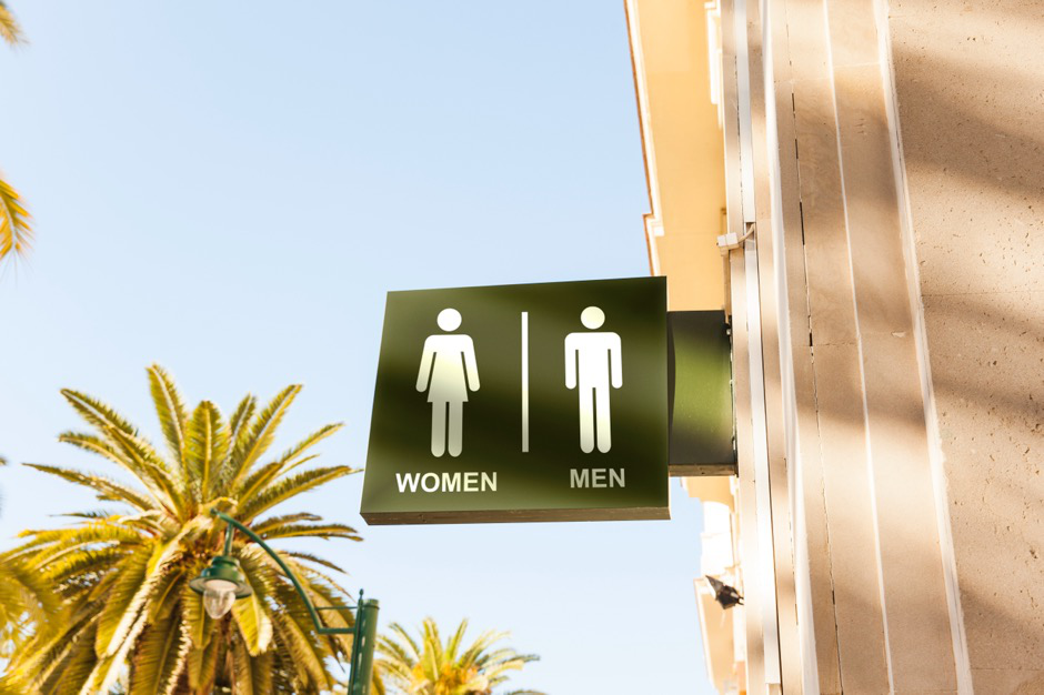A women’s and men’s restroom sign hanging from a building.