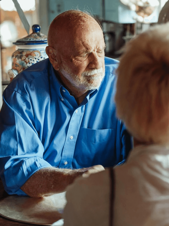  A concerned senior speaking with a caregiver, showing signs of stress or mental fatigue.
