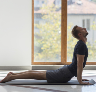 A person stretching indoors with a yoga mat nearby